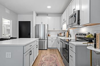 a white kitchen with stainless steel appliances and white cabinets